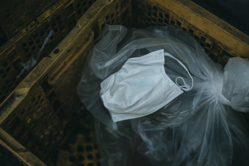 地面に散乱したゴミと一緒に投棄されたマスク