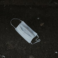 路上に捨てられた白いマスク、ポイ捨てによる感染リスクの写真