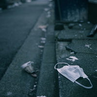 道路に散乱したポイ捨てされたゴミとマスクの写真