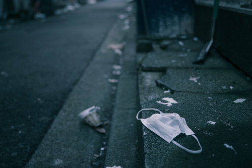 道路に散乱したポイ捨てされたゴミとマスク