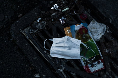 排水溝に引っかかったゴミとマスク、水の流れを妨げる廃棄物