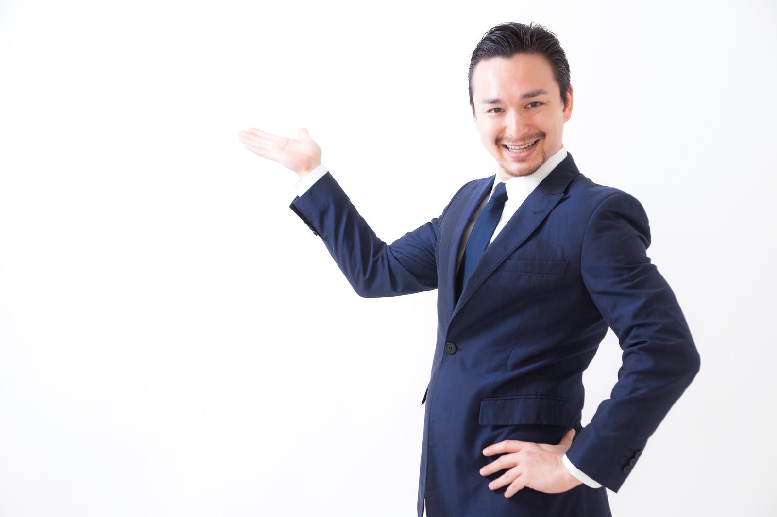 紺のスーツを着たドイツ人ハーフ男性が右手で製品を案内し笑顔で指している［モデル：Max_Ezaki］