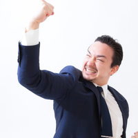 新規クライアントとの商談成功で拳を上げて叫ぶドイツ人ハーフ男性の写真