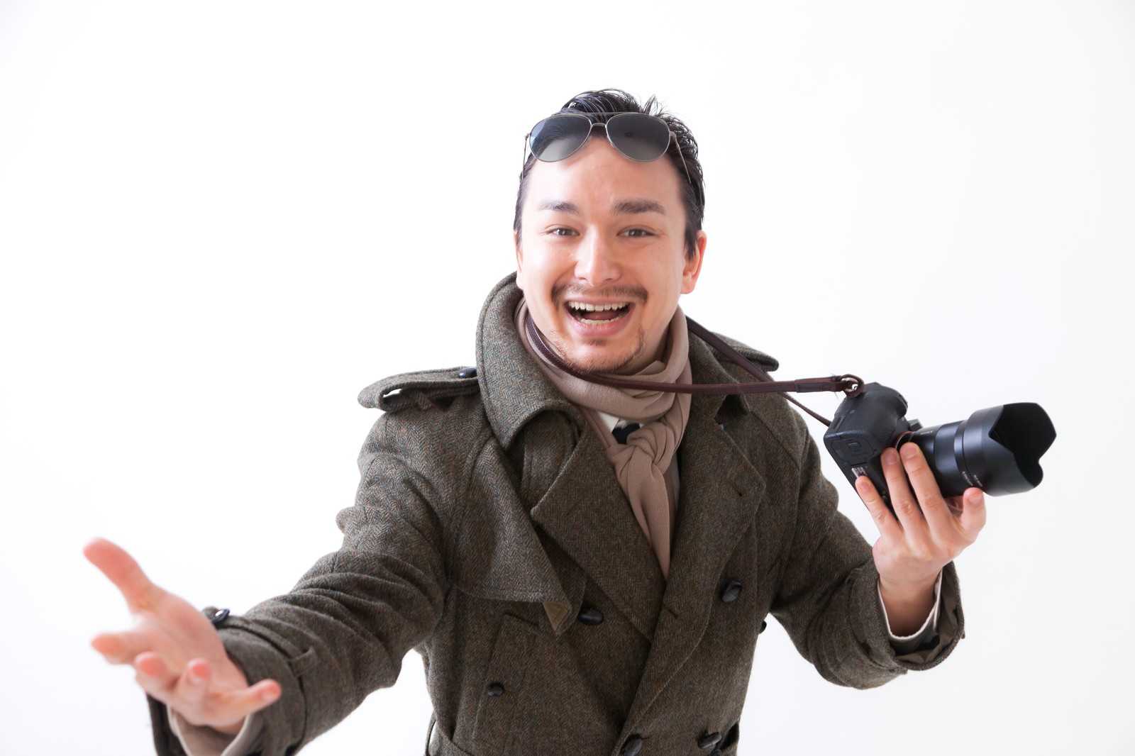 サングラスを額に乗せてカメラを持ちながらジェスチャーで話す男性カメラマン［モデル：Max_Ezaki］