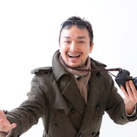 一眼レフカメラの素晴らしさを熱くジェスチャーで伝えるカメラマンの写真