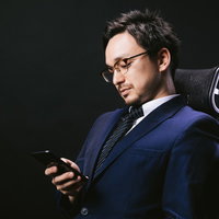 スマートフォンを見てうなだれる外資系ファンドマネージャーの写真