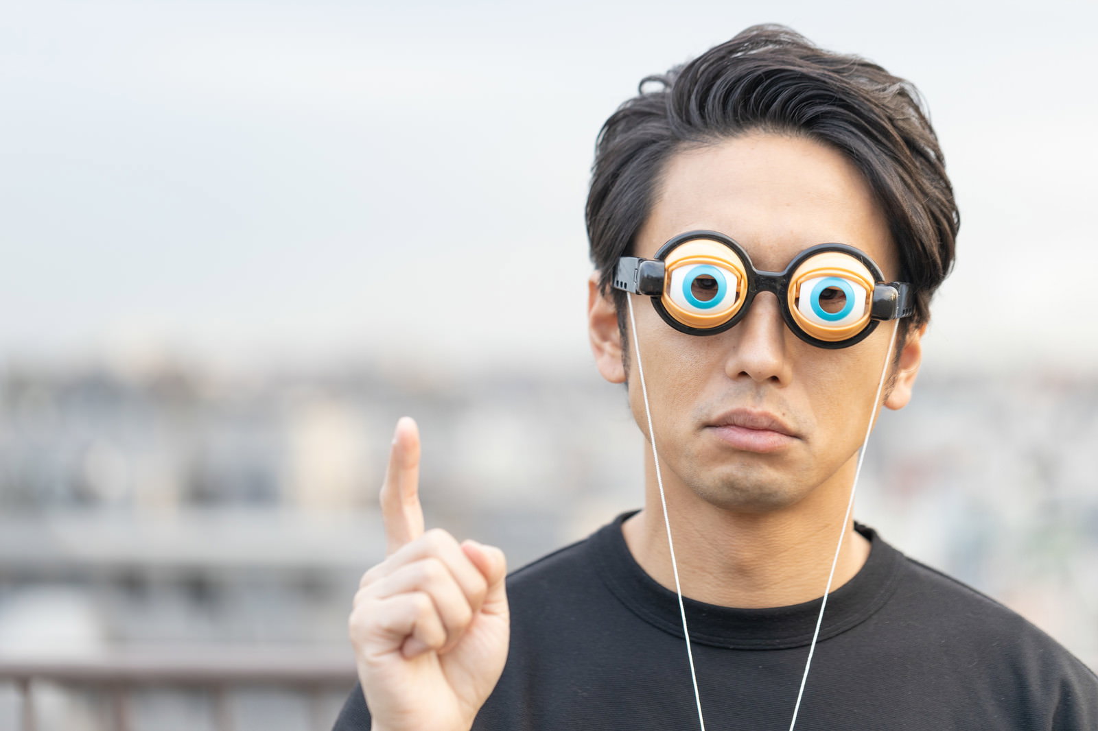 メガネをかけて人差し指を立てて何かを説明している男性［モデル：大川竜弥］