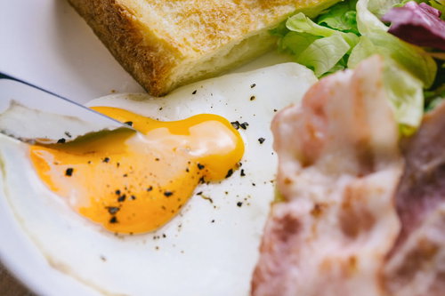 目玉焼きにナイフをさしてトロトロ黄身が流れるトースト朝食