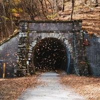 群馬の第六号トンネル入口の石造りアーチと秋の廃線跡の写真