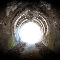 廃線トンネルを抜けて差し込む光の写真