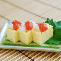 明太子入りの玉子焼き、白い皿に大葉を添えた和食のおかずの写真