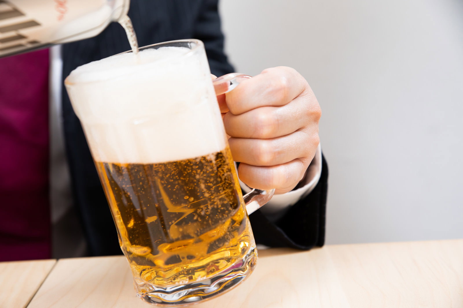 傾けたビールジョッキに黄金色のビールを注いでいる様子