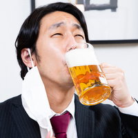 黙食しながらマスクをずらして飲む生ビールの写真
