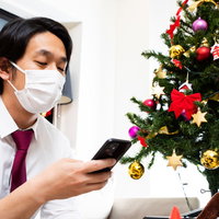 きっと君は来ない、マスク会食のクリスマス・イブ、スマホを見つめる男性の写真