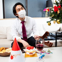 ソファーで一人クリスマスを迎えるスーツ姿の男性の写真