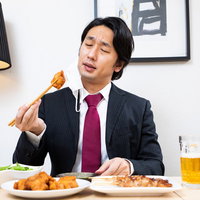 唐揚げに舌鼓を打つ会社員と生ビール、居酒屋での飲み会の写真