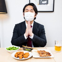 マスクをして合掌する黙食でいただきます。居酒屋での会食風景の写真