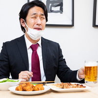 仕事終わりの一杯に顔が緩む会社員男性がジョッキで乾杯の写真