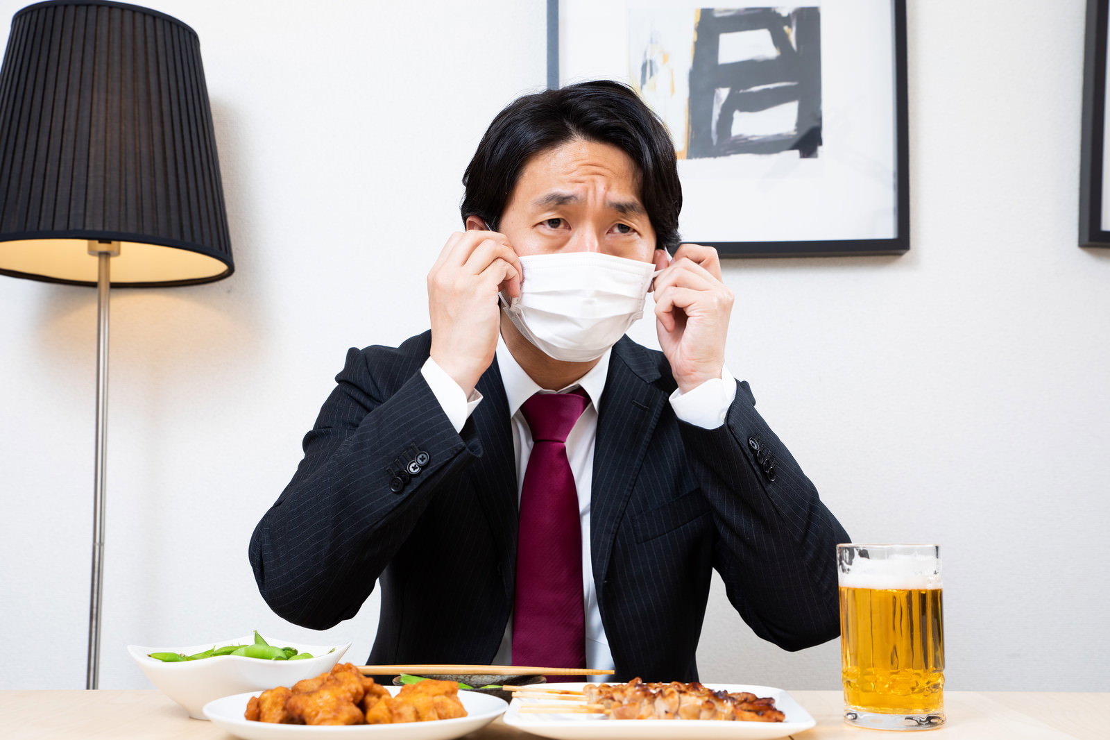 マスクをつけた男性が料理とビールを前にして黙食している様子［モデル：大川竜弥］