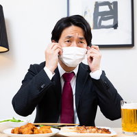 黙食で飲み会をする男性、生ビールと料理で乾杯の写真