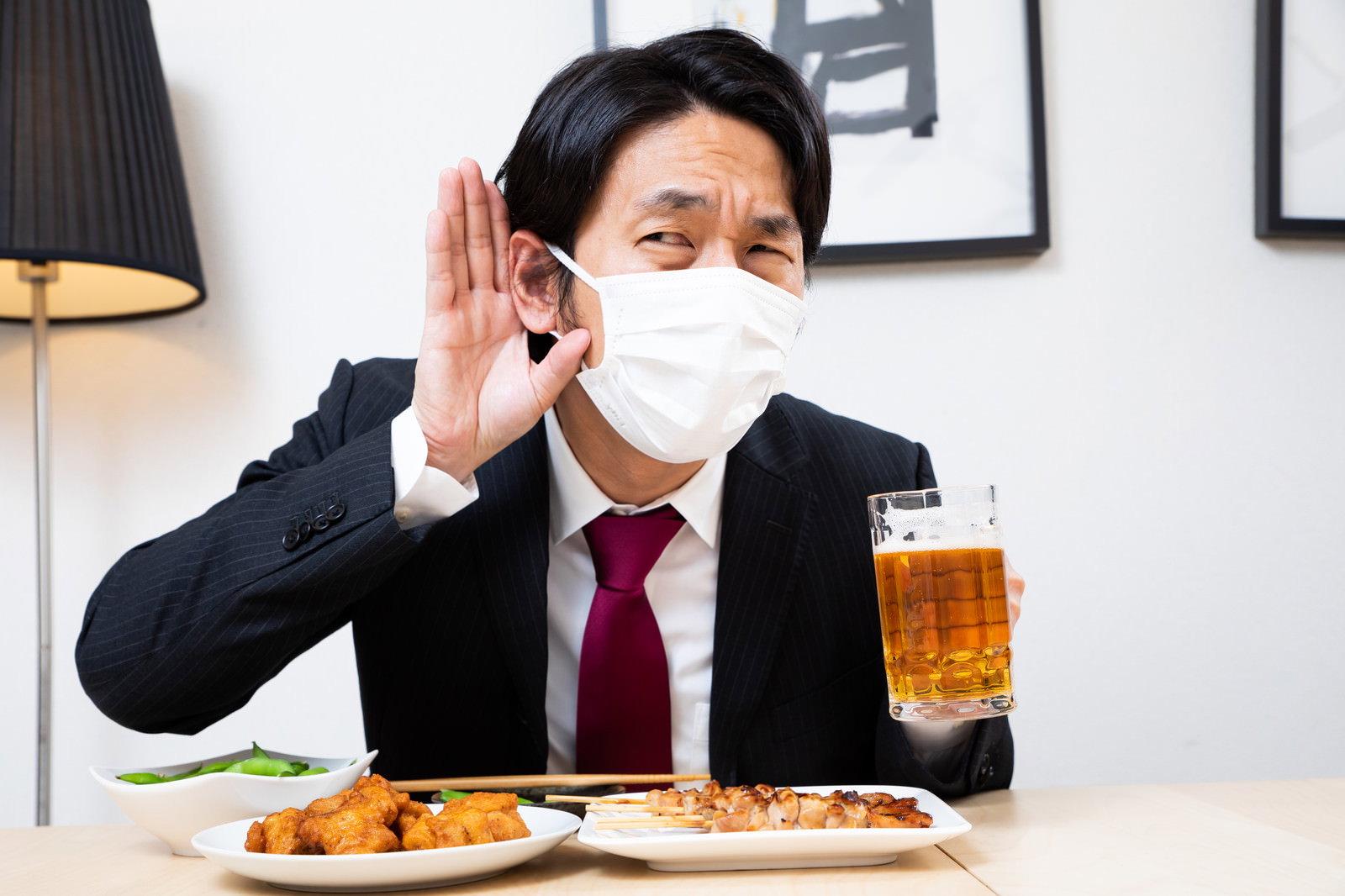 マスクを着用した男性が手を耳に当てて聞き取ろうとしている［モデル：大川竜弥］