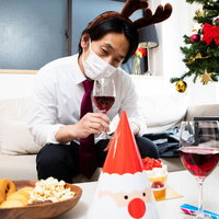 マスク会食で仮装してもしょんぼり、赤ワインを片手にするクリスマスパーティー男性の写真