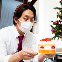 小振りのクリスマスケーキを見つめるクリボッチャー男性の写真