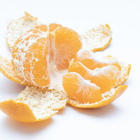 皮を剥いたみかんの房と散らばった皮の写真