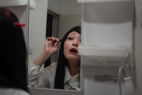 当選したから鏡の前で黒目を描く女性