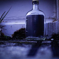 薄暗い裏路地に放置された空き瓶の写真