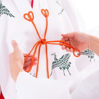 巫女の千早に赤い紐を結ぶ手元の作業風景の写真