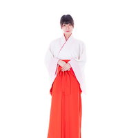 巫女装束を着た女性が神社で立つ姿の写真