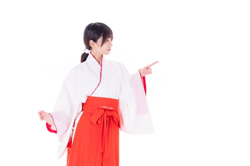 初詣の参拝はあちらですと案内する巫女