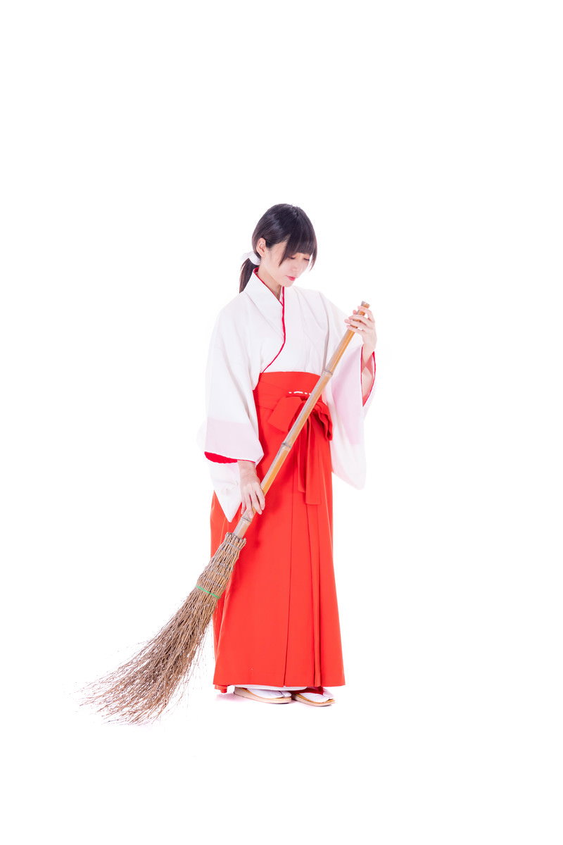 白い上衣と赤い袴を着た巫女さんが竹ほうきを持って掃除をする様子［モデル：緋真煉］