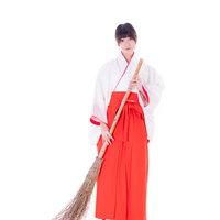 おでかけですか？竹箒を持つ巫女が神社で掃除作業の写真