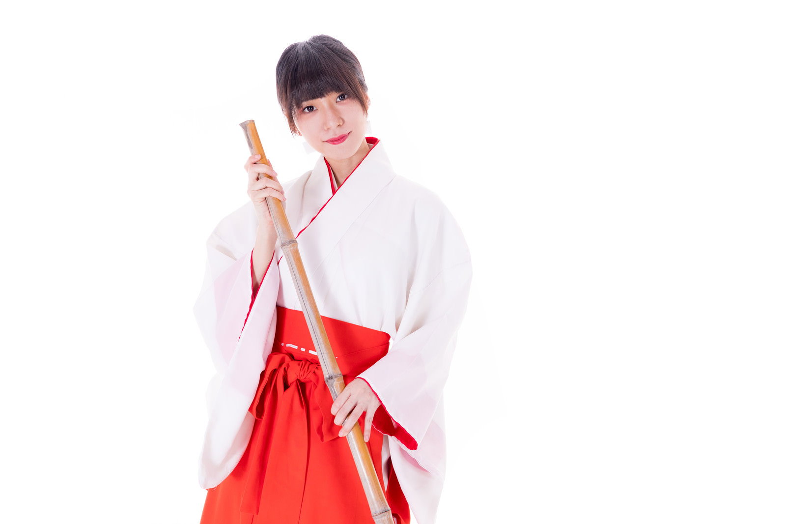 竹箒で掃き掃除をする巫女装束の女性［モデル：緋真煉］