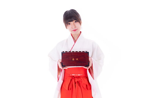 賽銭はこちらからと案内する巫女の神社参拝