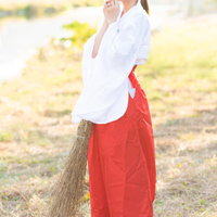 ほうきを持って夕日を眺める巫女さんの写真