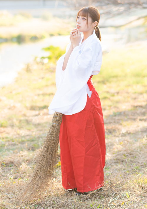 ほうきを持って夕日を眺める巫女さん