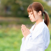 目を閉じて手を合わせお祈りする巫女の参拝風景の写真