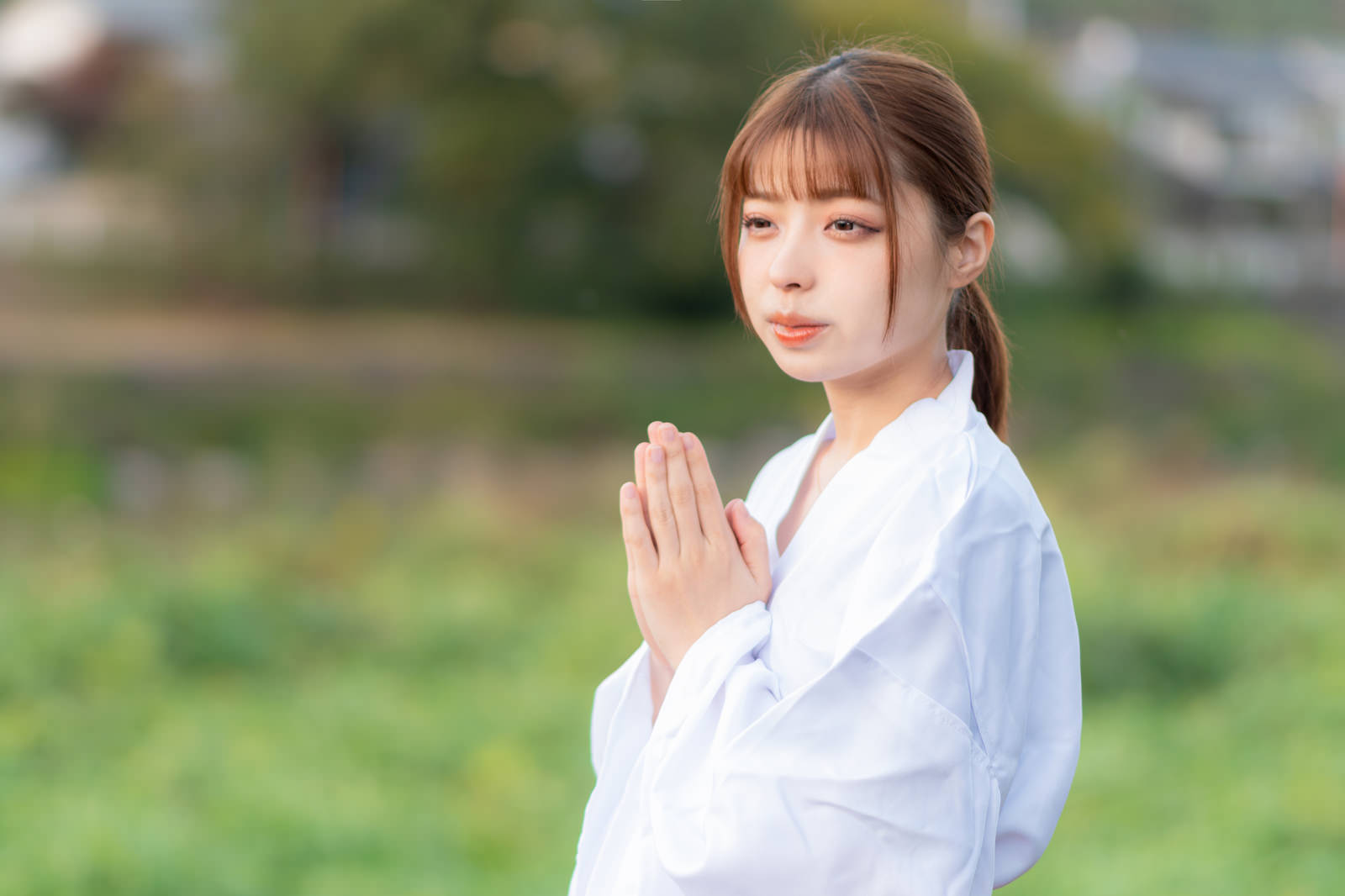 白い装束を着た女性が目を閉じて両手を合わせて祈っている［モデル：高尾実生］