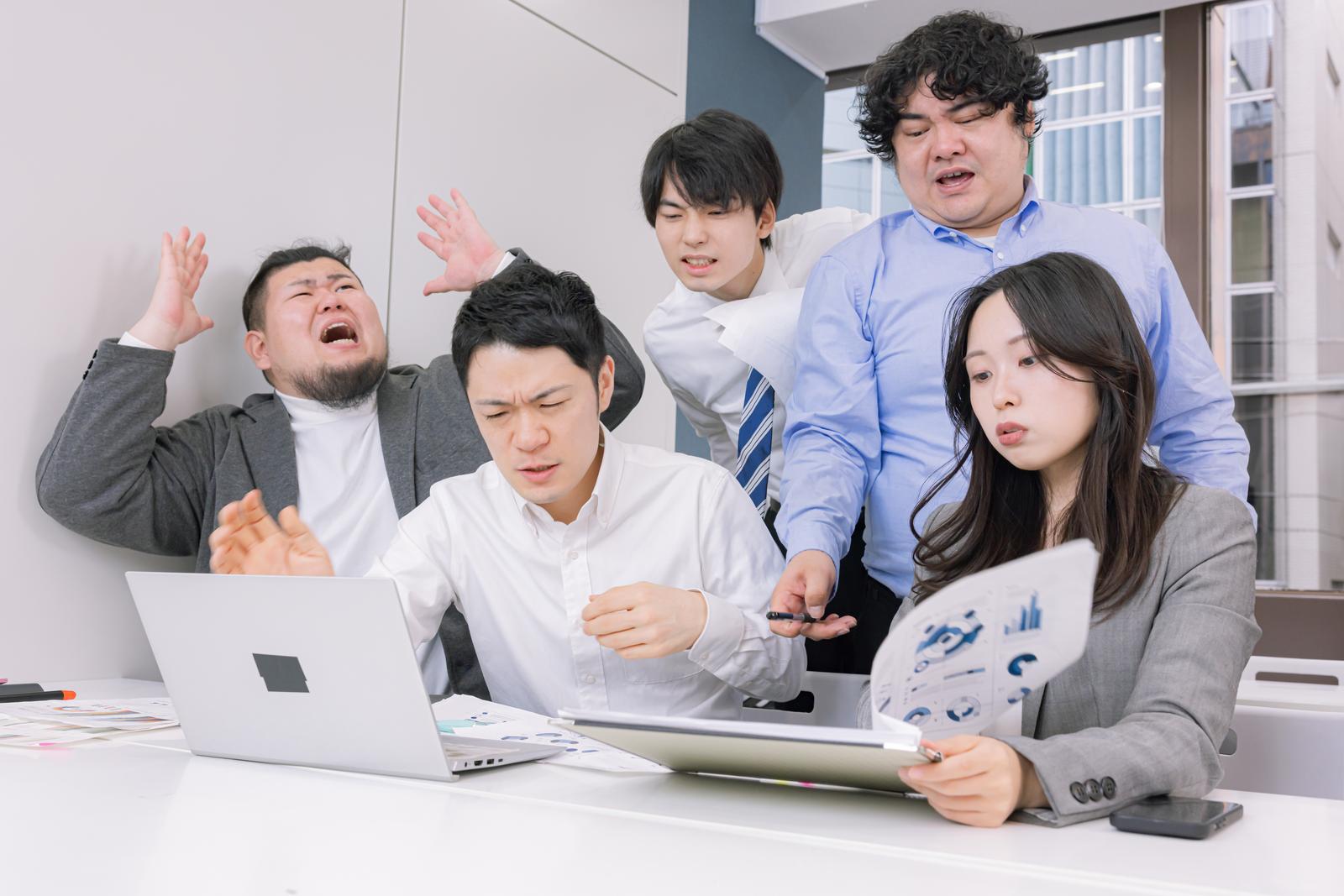 オフィスのミーティングで複数のビジネスマンが資料を前にして意見交換をしている場面［モデル：たくみ 吉屋ゆり 段田隼人 ノリックス モデルリリース］