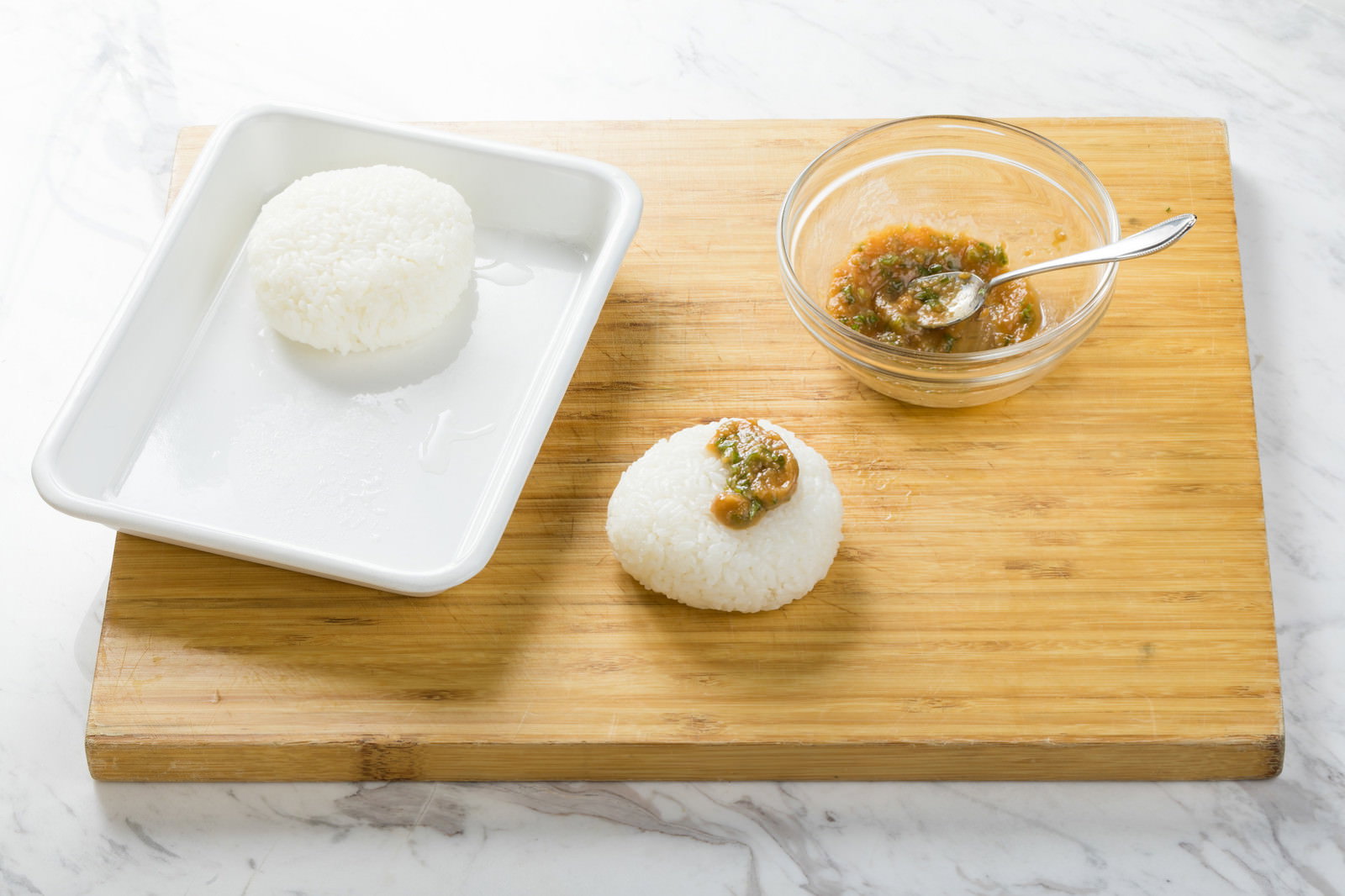 白い皿に盛られたおにぎりに刻んだししとうと味噌が乗せられている