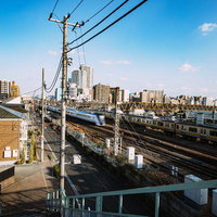 三鷹跨線人道橋から見えるJR三鷹駅方面の線路と町並みの写真
