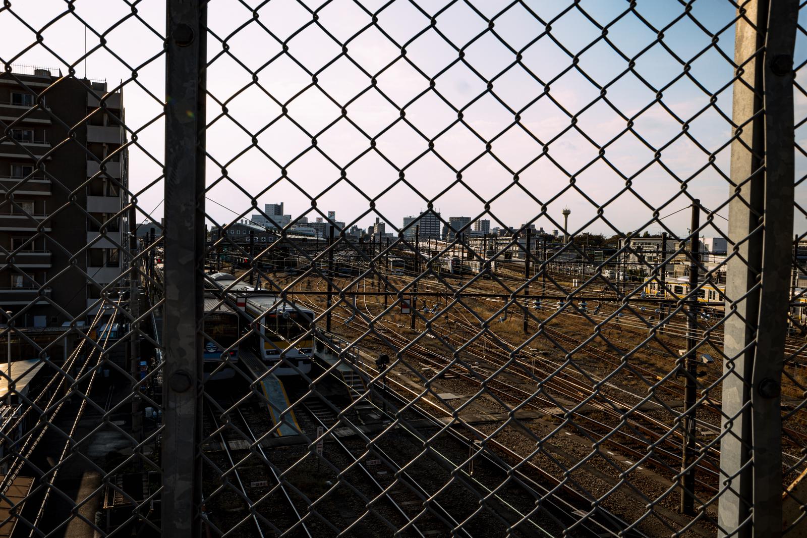 三鷹跨線橋の金網フェンス越しに見えるJR車両センターと線路