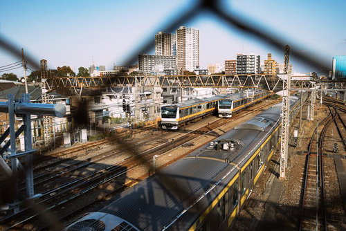 三鷹の陸橋から金網越しに見る中央線と駅周辺の町並み