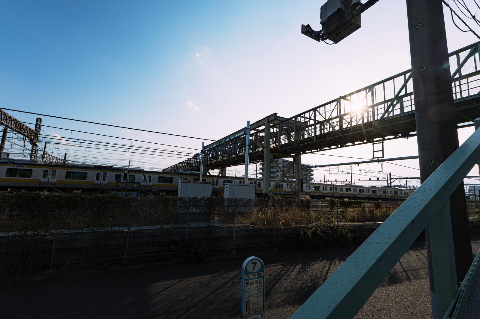JR三鷹駅の上空に架かる跨線橋と駅前のバス停標識
