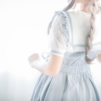 白いエプロンドレスの三編み少女の後ろ姿の窓辺撮影の写真