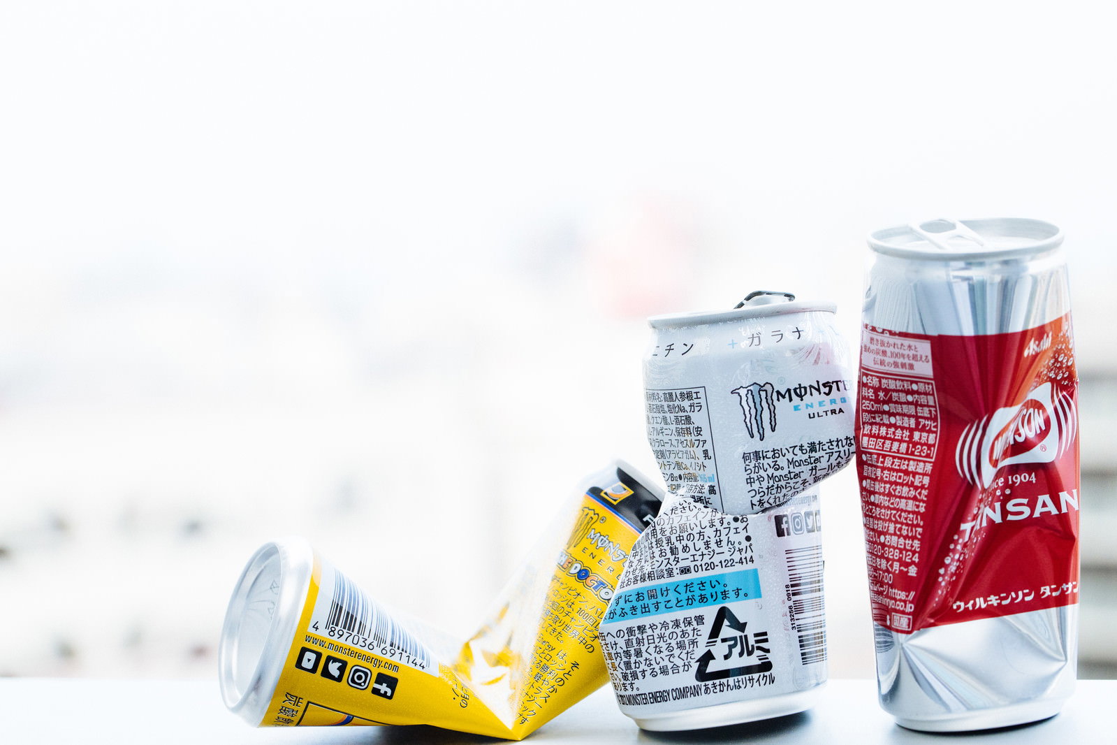 テーブルの上に並べられた3つの空き缶（黄色、白色、赤色）