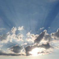 空に広がる夕陽の光芒と雲のグラデーションの写真